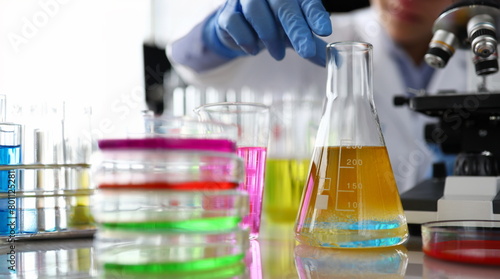 Chemistry industry lubricant oil test concept. Female chemist in blue protective gloves hand hold test tube with yellow liquid. Make analysing sample petroleum gasoline fuel in chemical laboratory.