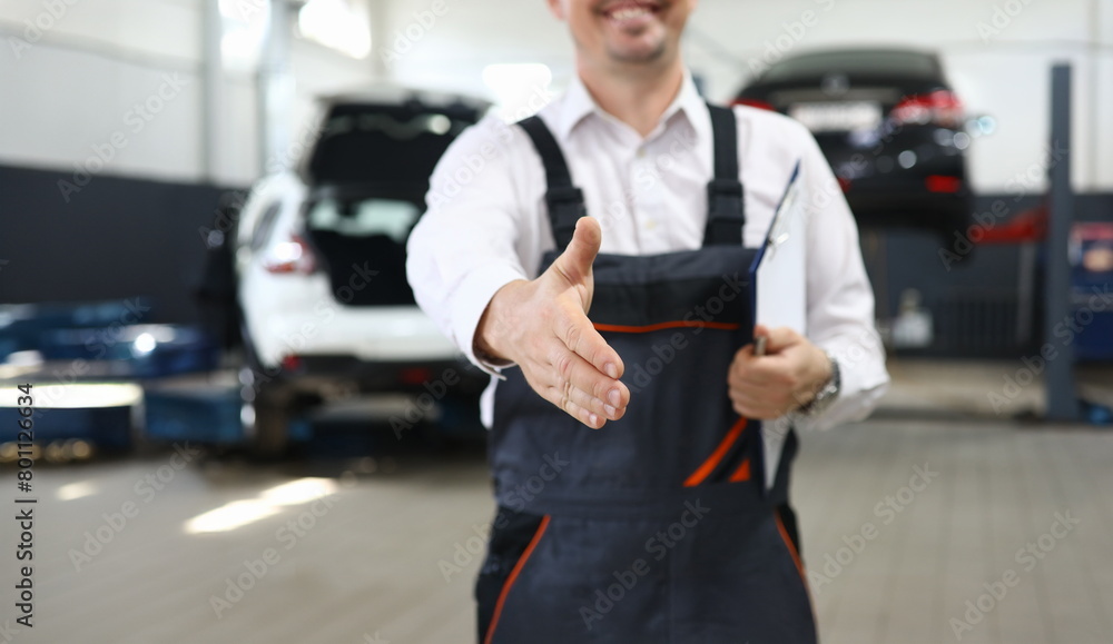 Fototapeta premium Focus on smart man hand reaching for firm handshake with someone and holding important paper folder with information about different autos. Machinery repairman concept