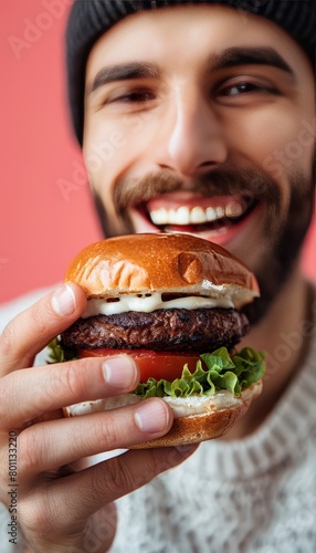 Man enjoying tasty burger in portrait on soft colored backdrop with room for text