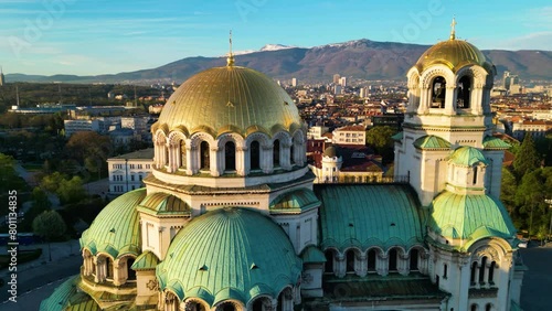 Aerial shot of the Patriarchal Cathedral of St. Alexander Nevsky in Sofia Bulgaria. High angle footage of the iconic Bulgarian orthodox church during sunrise surrounded by green trees. Golden hour.
 photo