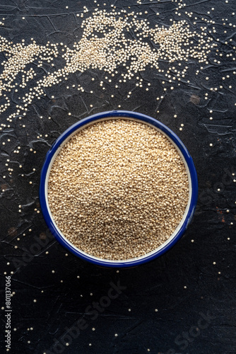 Quinoa in a bowl, healthy organic wood, uncooked, overhead shot on a black table