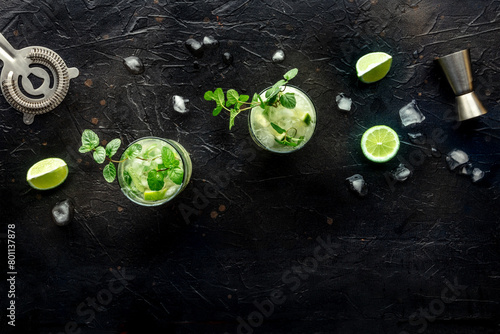 Mojito cocktail. Summer cold drink with lime, fresh mint, and ice. Cool beverage on a black background, shot from above with a place for text