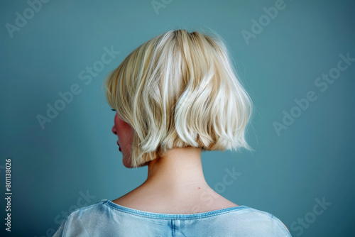 Blonde girl with short hair on a gray background. Back view