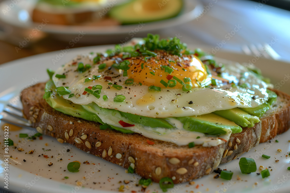 Avocado on toast topped with a fried egg and spring onion served on a white plate