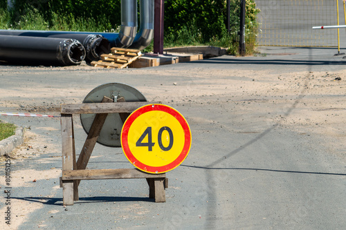 A wooden sign with a red circle and a yellow number 40 sits on a wooden post. The sign is placed in front of a fence