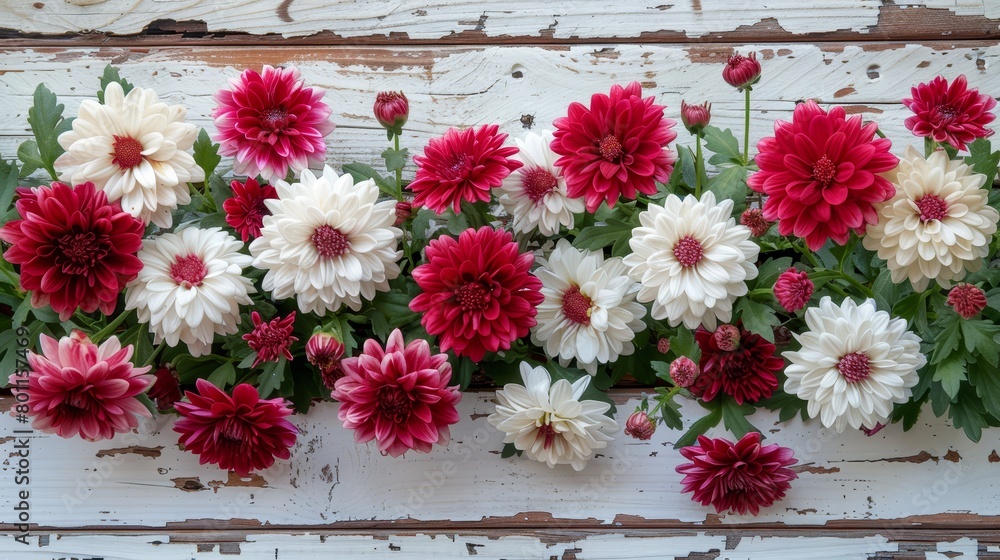   A tight shot of an arrangement of flowers against a white wooden backdrop Red and white blooms occupy the center