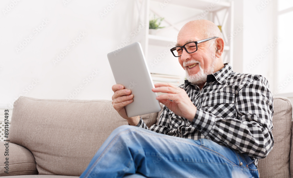 Obraz premium Senior man reading news on digital tablet