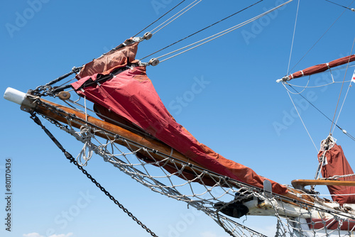 Ship's bow with jib boom and knotted jib net in front of the foremast of a moored sailing ship, stretched between the two bow stays at blue sky photo
