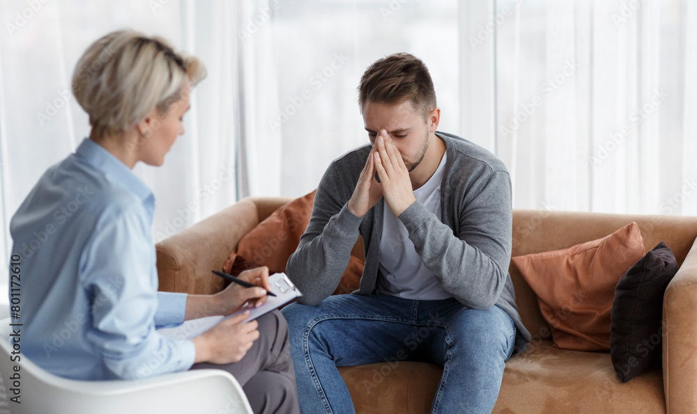 Desperate Man Telling About Life While Psychologist Taking Notes Indoors Desperate Man Telling About Life While Psychologist Taking Notes Indoors