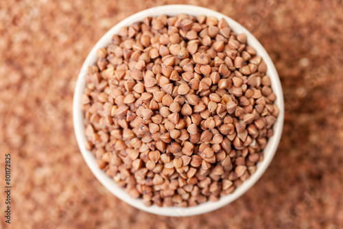 Uncooked, brown buckwheat grains in bowl. Dry buckwheat grains. Healthy food