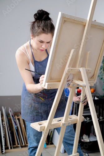 Young female artist paints a picture with oil on canvas in art studio