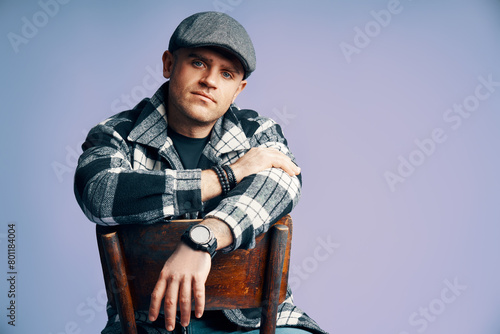 Stylish handsome man posing sitting on the chair on blue studio background