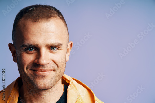 Close-up portrait of handsome young man looking to camera over soft blue background