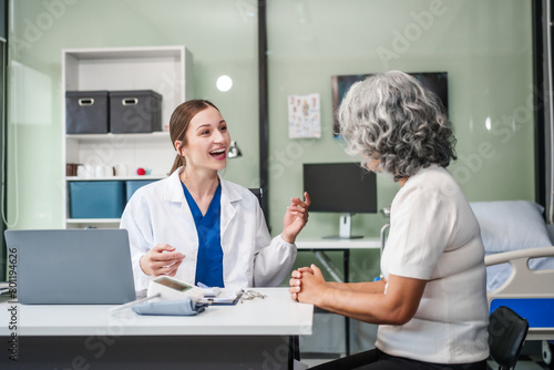 Monthly health check-ups and counseling sessions are provided to an elderly Asian woman by a Caucasian female caregiver, offering support, advice, and motivation.