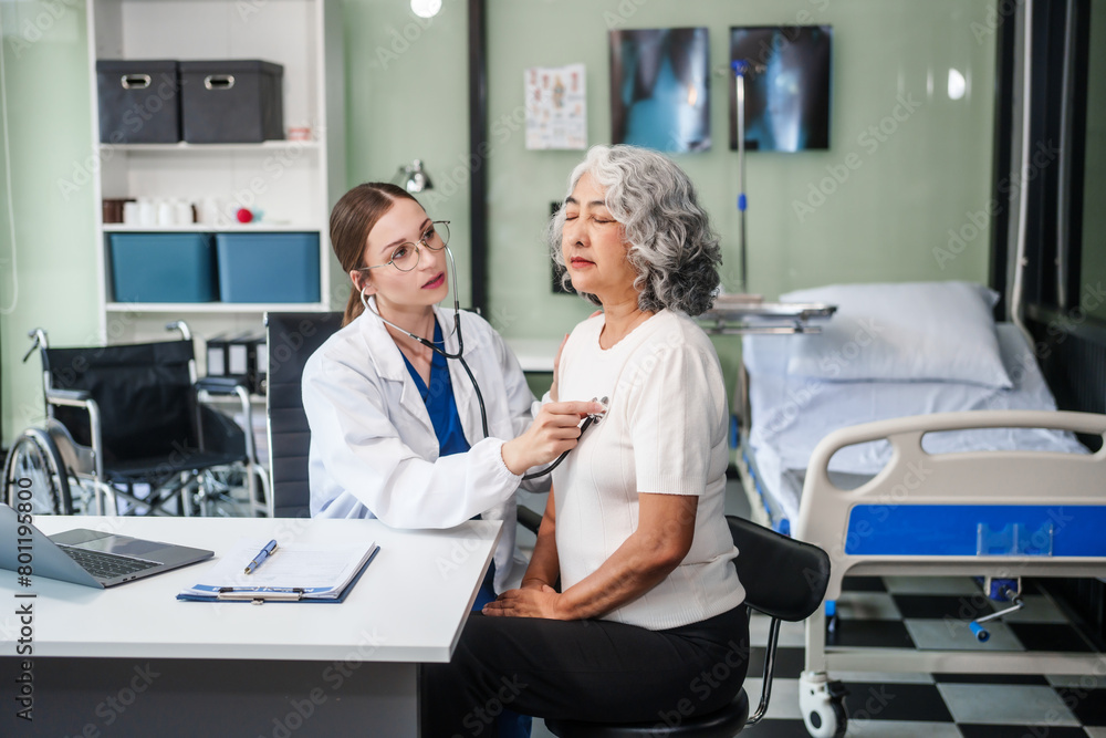 Obraz premium Caucasian woman checks an Asian elderly woman's heartbeat using a stethoscope. They communicate calmly and kindly.