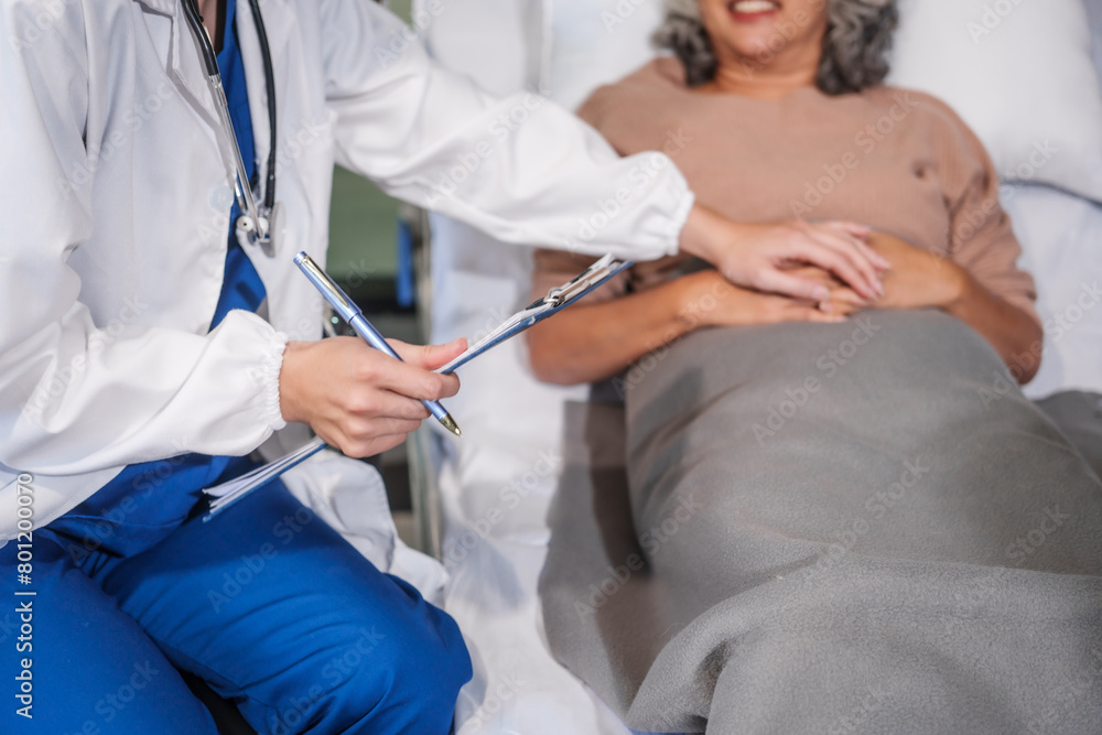 Caucasian female specialist doctor attends to an elderly Asian female patient in a hospital bed, providing medical care and support. Caucasian female specialist doctor attends to an elderly Asian female patient in a hospital bed, providing medical care and support.
