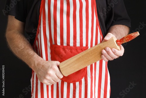 An angry and impatient baker brandishing a wooden rolling pin