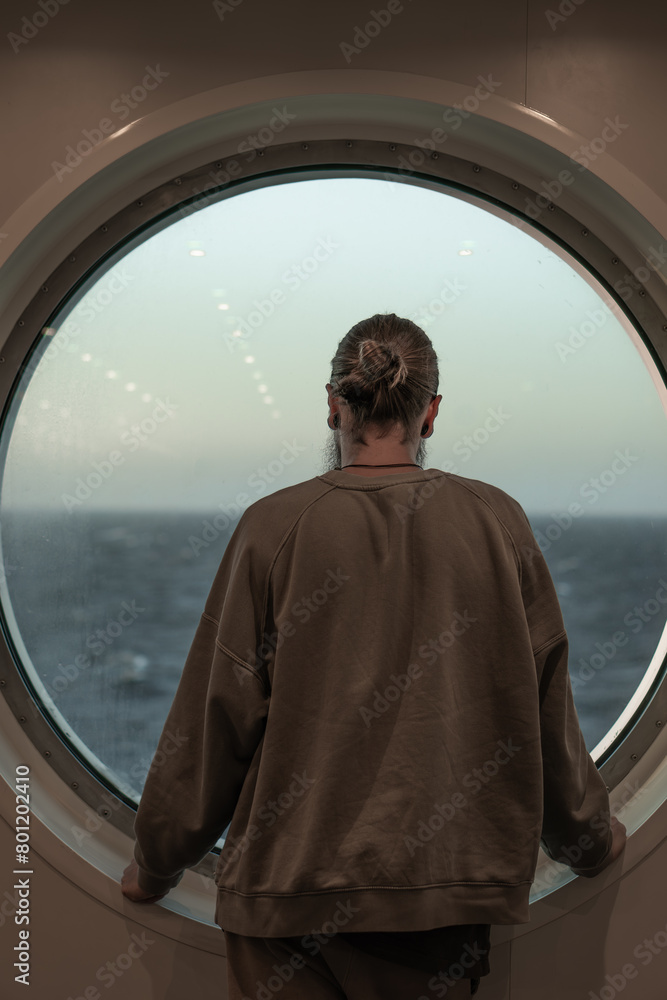 Fototapeta premium man looking out the ship's window