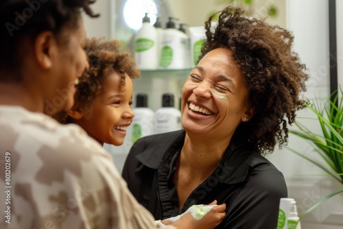 Black women are laughing and smiling, preparing for the day in the bathroom with hydrating cream photo
