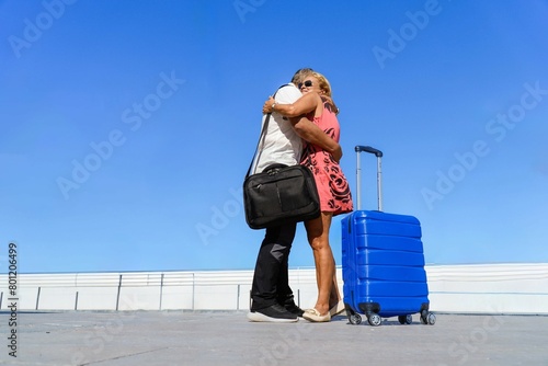 an adult couple traveler hugs each other with their luggage in the airport. Traveling and family