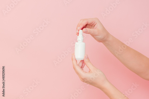 Glass cosmetic bottle for serum (hyaluronic acid and collagen) in hand on pink background. Beauty concept © Anton Tolmachov
