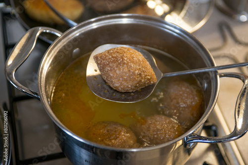 cooking meatballs in a pot on a gas stove in the kitchen . Ishli kufta
