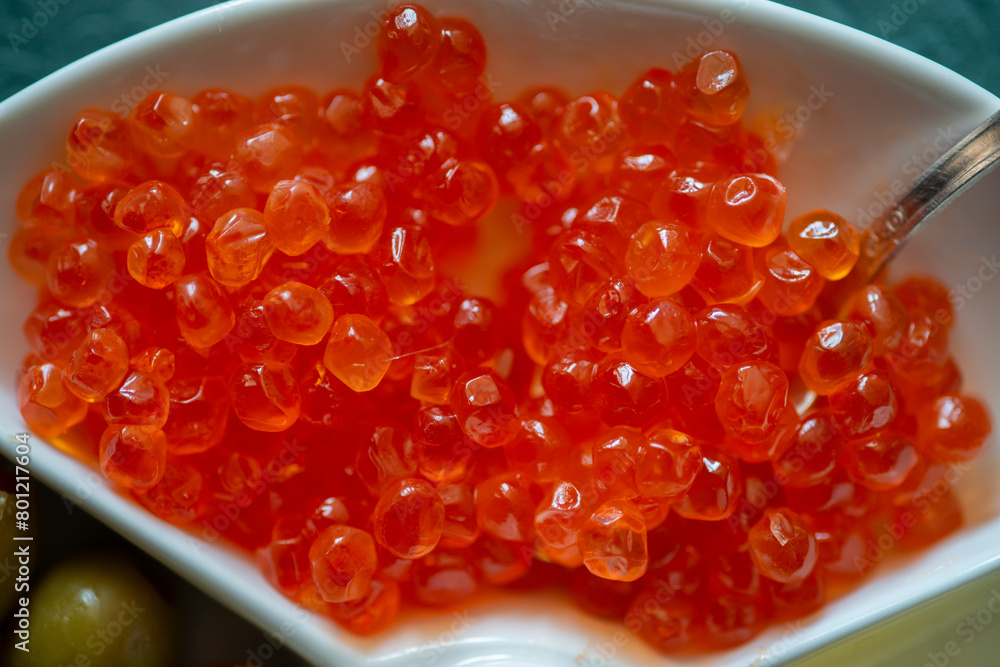 Red caviar in a white plate with olives, cheese and spoon Red caviar in a white plate with olives, cheese and spoon
