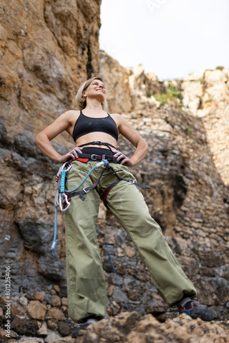 A woman in a green pair of pants stands on a rocky cliff