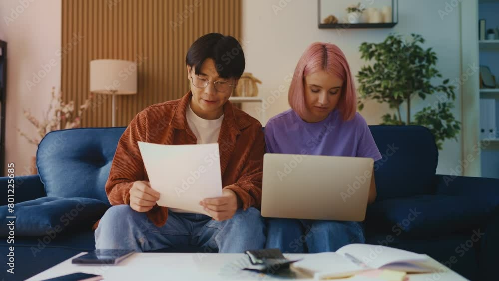 Young multiethnic couple calculating family budget, planning a vacation at home Young multiethnic couple calculating family budget, planning a vacation at home