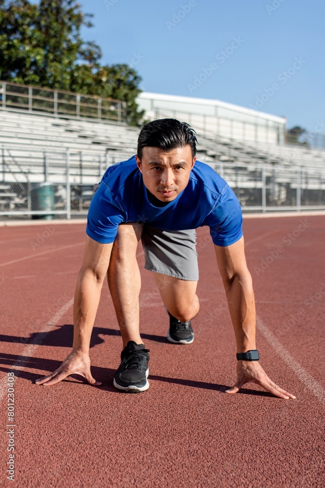 Asian man getting ready to take off on the running track Asian man getting ready to take off on the running track