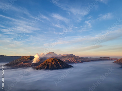 Sunrise view from Penanjakan 2 or Seruni point below shows the fog still covering the sea of sand and the front view of Mount Batok with Mount Bromo behind it still emitting volcanic smoke. photo