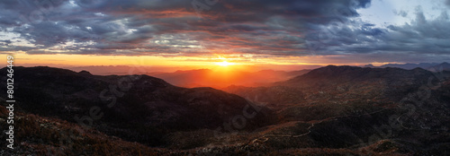 Panorama of a mountain landscape with a brilliant sunset between the land and the clouds.