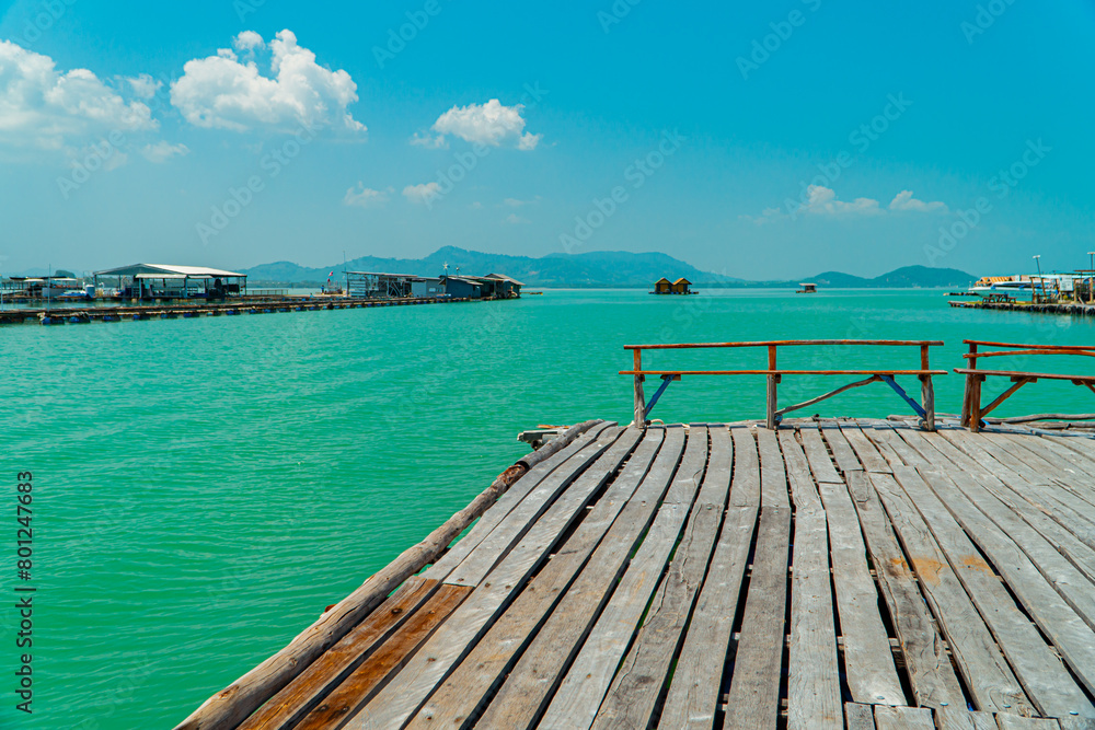 Obraz premium Small floating houses between the horizon line that separates the sea from the sky and set against a backdrop of plains and mountains. Floating houses used by fishermen as a place to cultivate fish
