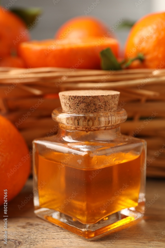 Bottle of tangerine essential oil and fresh fruits on wooden table, closeup Bottle of tangerine essential oil and fresh fruits on wooden table, closeup