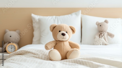 A cute teddy bear sitting on a bed with a clock and another toy in the background