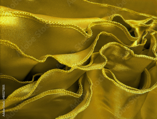 edge of the fabric with wavy stitching or overlock. a collection of thin, golden yellow cotton fabric with wavy edge stitching. thin sewing fabric. fabric with soft textured folds. handycrafts photo