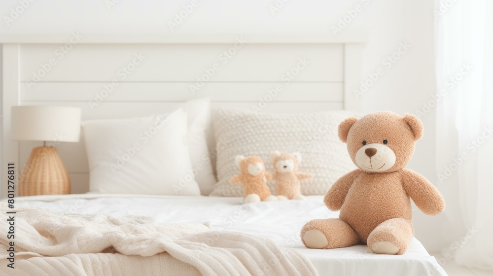 A cute teddy bear sitting on a bed with a white blanket and pillows