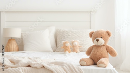 A cute teddy bear sitting on a bed with a white blanket and pillows