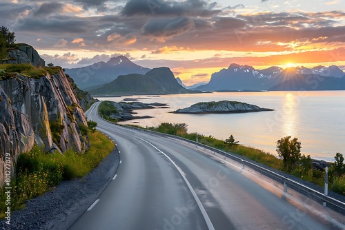 A beautiful road along the sea in Norway, with an ocean view and mountains on both sides. The sun sets behind them, casting warm hues across the sky