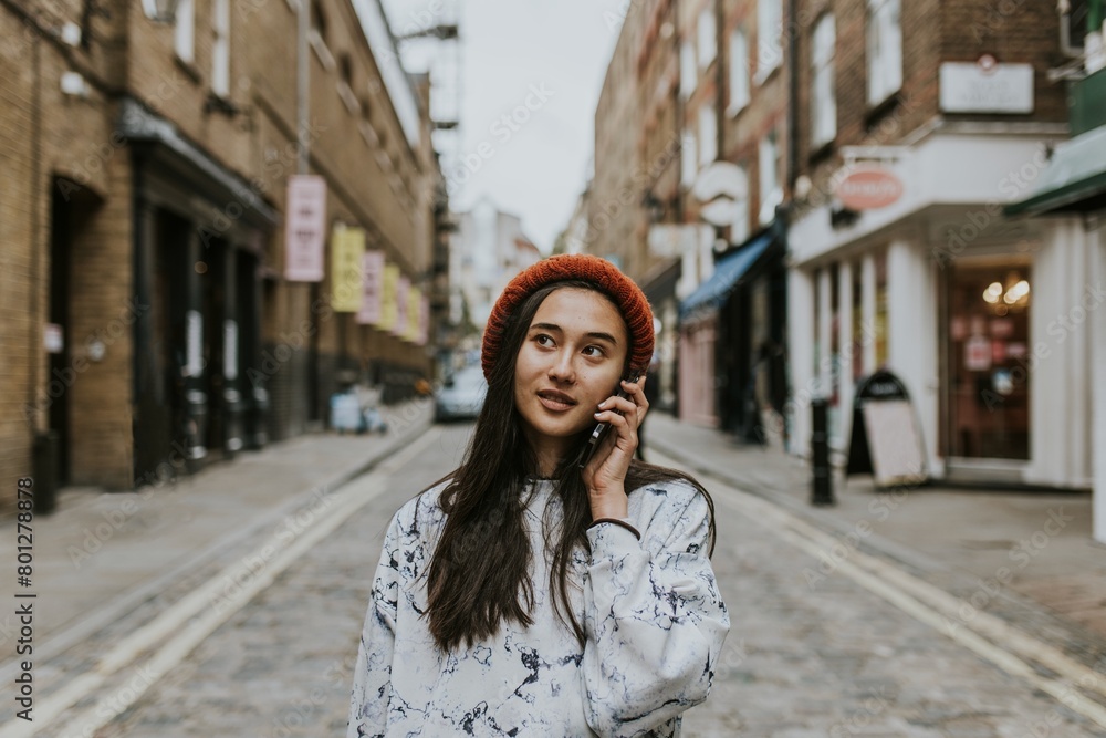 Fototapeta premium Young woman talking on a phone while in a city