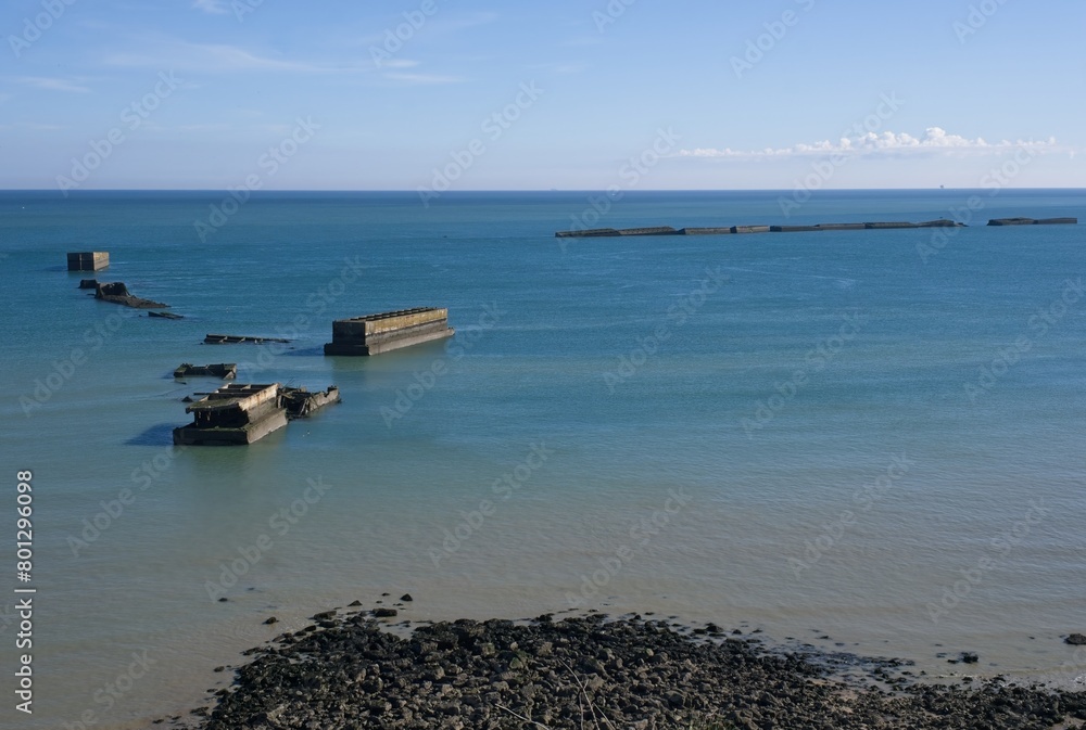 Tracy-sur-Mer, France - Apr 29, 2024: What remain of Arromanches artificial port (Mulberry B) during Second World War. Whale and Phoenix Caissons. Selective focus.