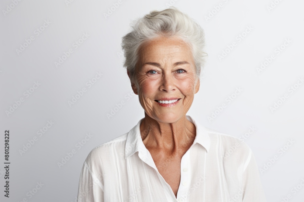 Portrait of a blissful woman in her 70s wearing a simple cotton shirt over white background Portrait of a blissful woman in her 70s wearing a simple cotton shirt over white background