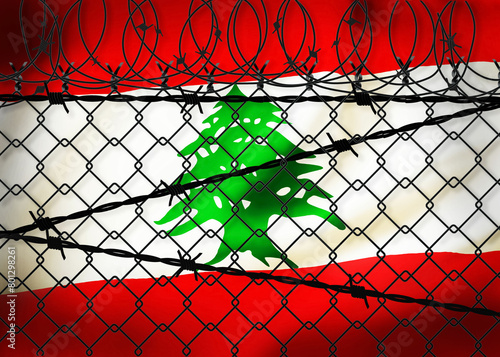 Lebanon flag behind barbed wire and metal fence