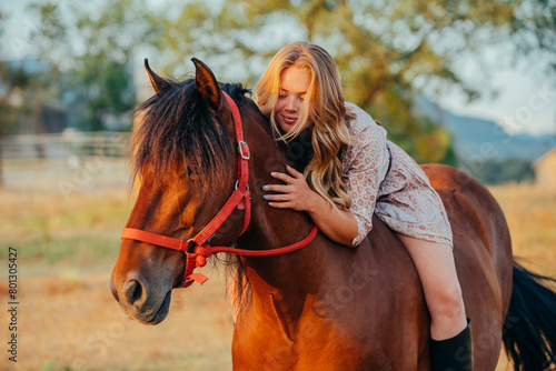 Portrait of a young cheerful caucasian woman hugging her horse at countryside during sunset. Lifestyle concept. © carlesmiro