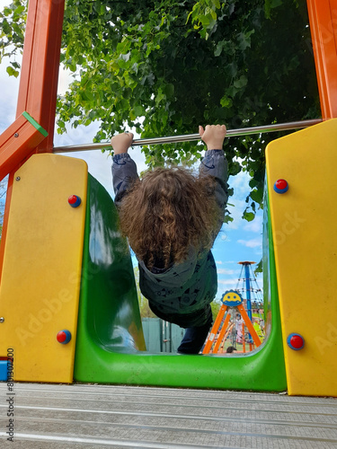 Bambino che gioca sullo scivolo al parco giochi in primavera photo