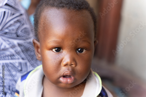 african village, small child in front of the house on the porch , mother in the background © poco_bw
