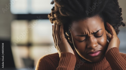 A worried African American businesswoman with neck ache in an office. Entrepreneur rubbing muscles and body from incorrect sitting position and extended desk hours when stressed photo