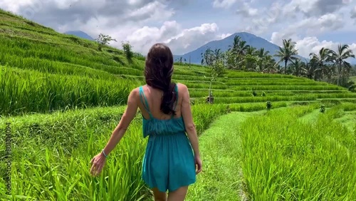  The girl happily waves her hands enjoying the sunny weather and the beautiful view of the rice terraces and mountains. A woman walks through a rice field, touching the tall grass with her hands