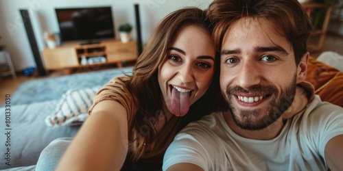 Funny romantic couple pulling faces and fooling around while holding a mobile phone and taking a selfie together. Fun couple taking a picture or video call. photo