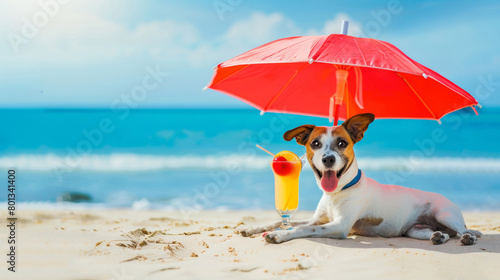 A dog is laying on the beach with a cocktail drink and red umbrella. The dog is smiling and he is enjoying the sunny day. Sandy beach and ocean wave in the background.